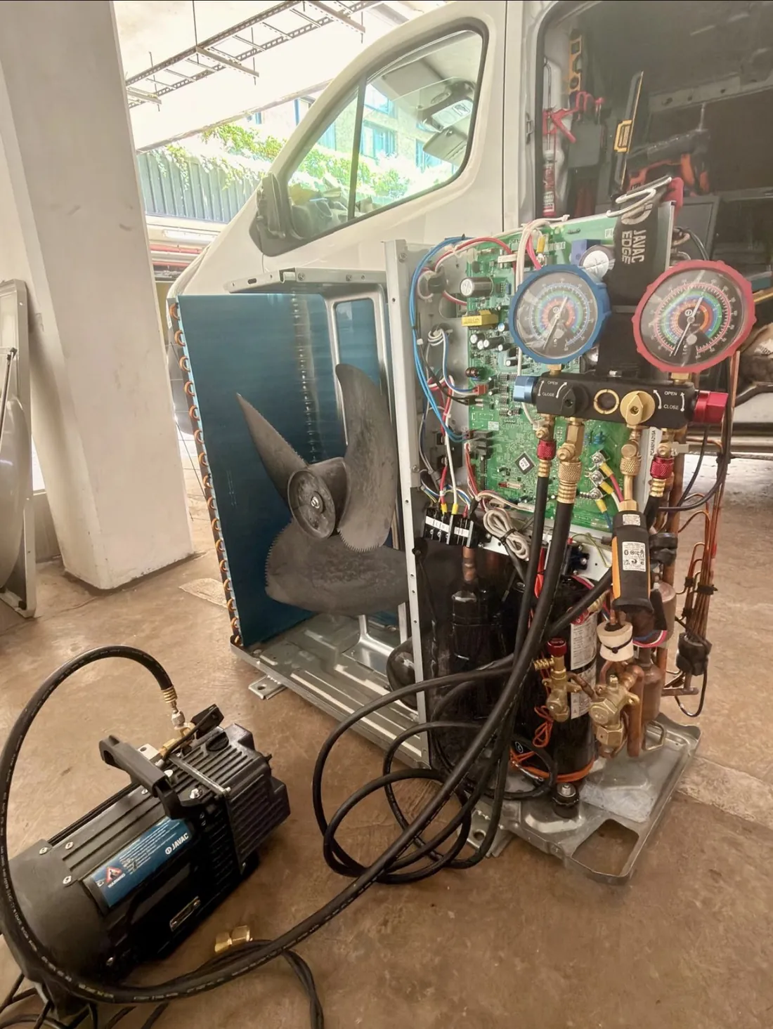 Air conditioning outdoor unit opened up for repair with vacuum pump and manifold gauges connected