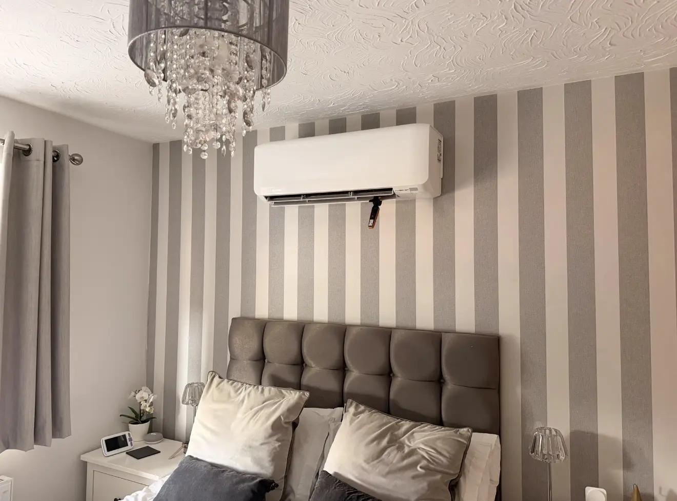 Wall-mounted air conditioning unit installed above a bed