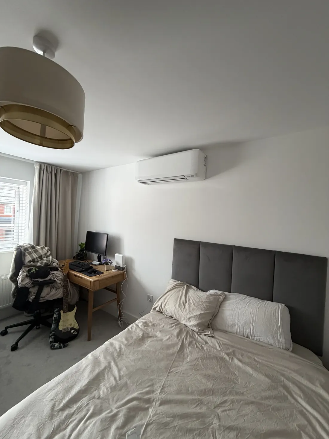 Wall-mounted air conditioning above a bed in a modern bedroom