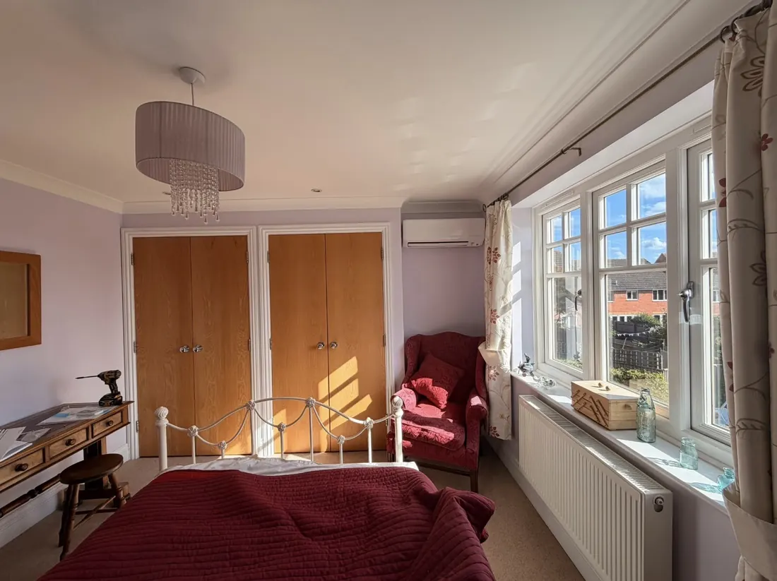 Bedroom with a wall-mounted air conditioning unit above the window corner