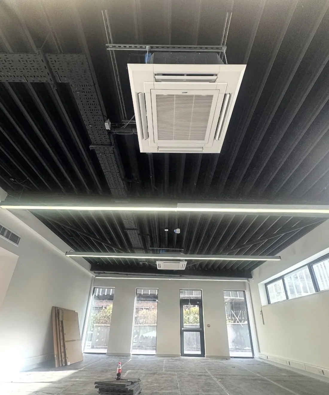 Four-way ceiling cassette suspended below a black soffit in a new commercial unit