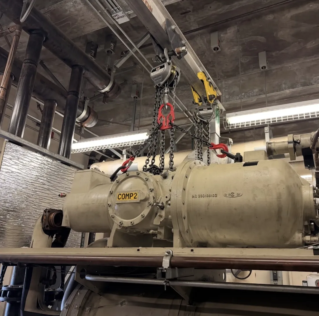 Screw compressor on a chiller being lifted with chain hoists during a plant room overhaul