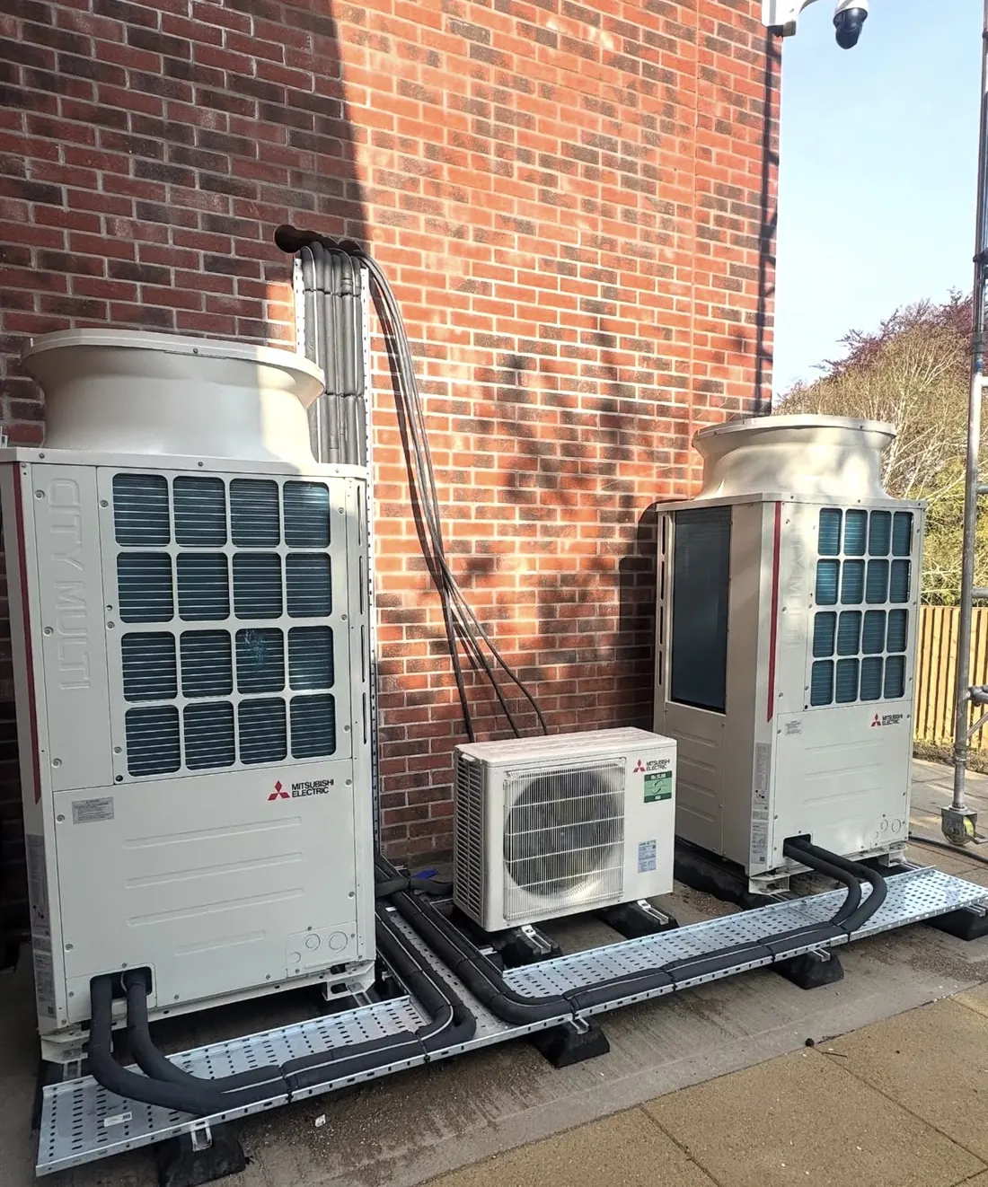 Mitsubishi Electric City Multi outdoor units on a brick wall with pipework in galvanised tray