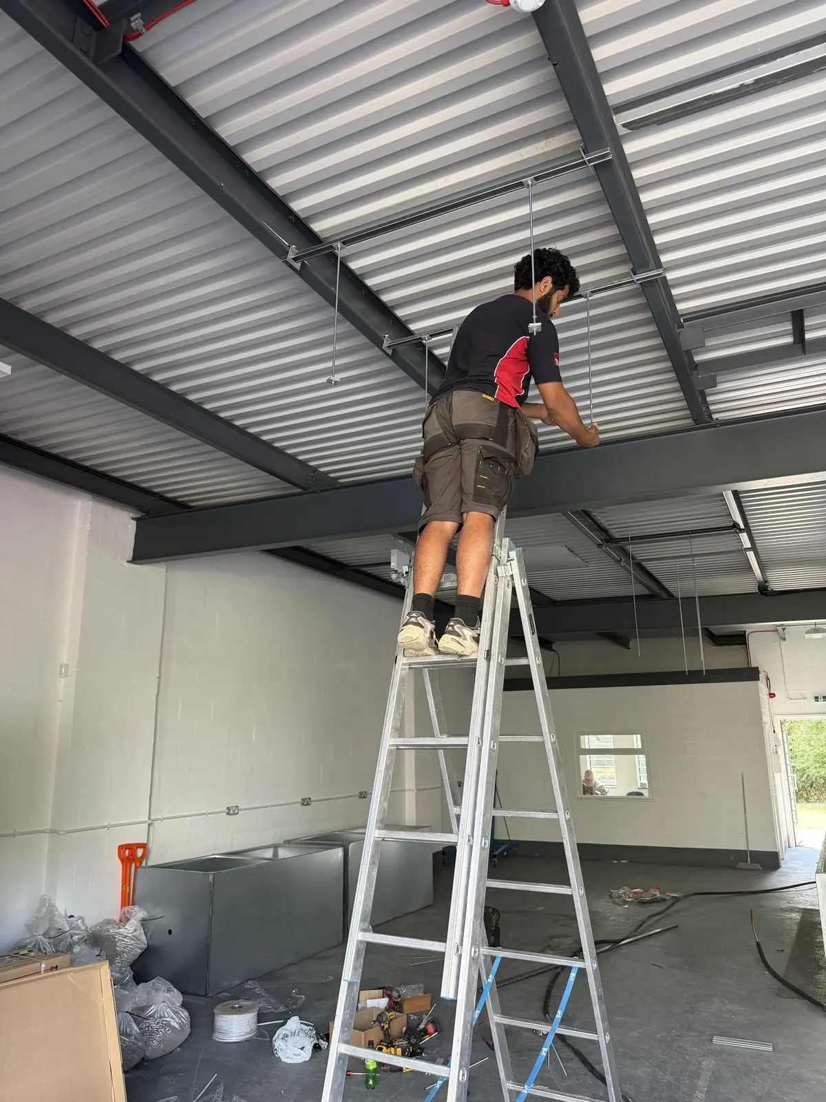 Engineer installing ceiling cassette supports in a commercial unit