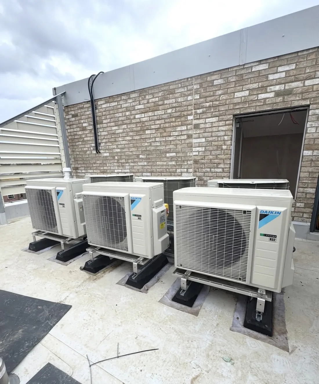 Row of Daikin R32 outdoor units on anti-vibration feet on a new-build roof terrace