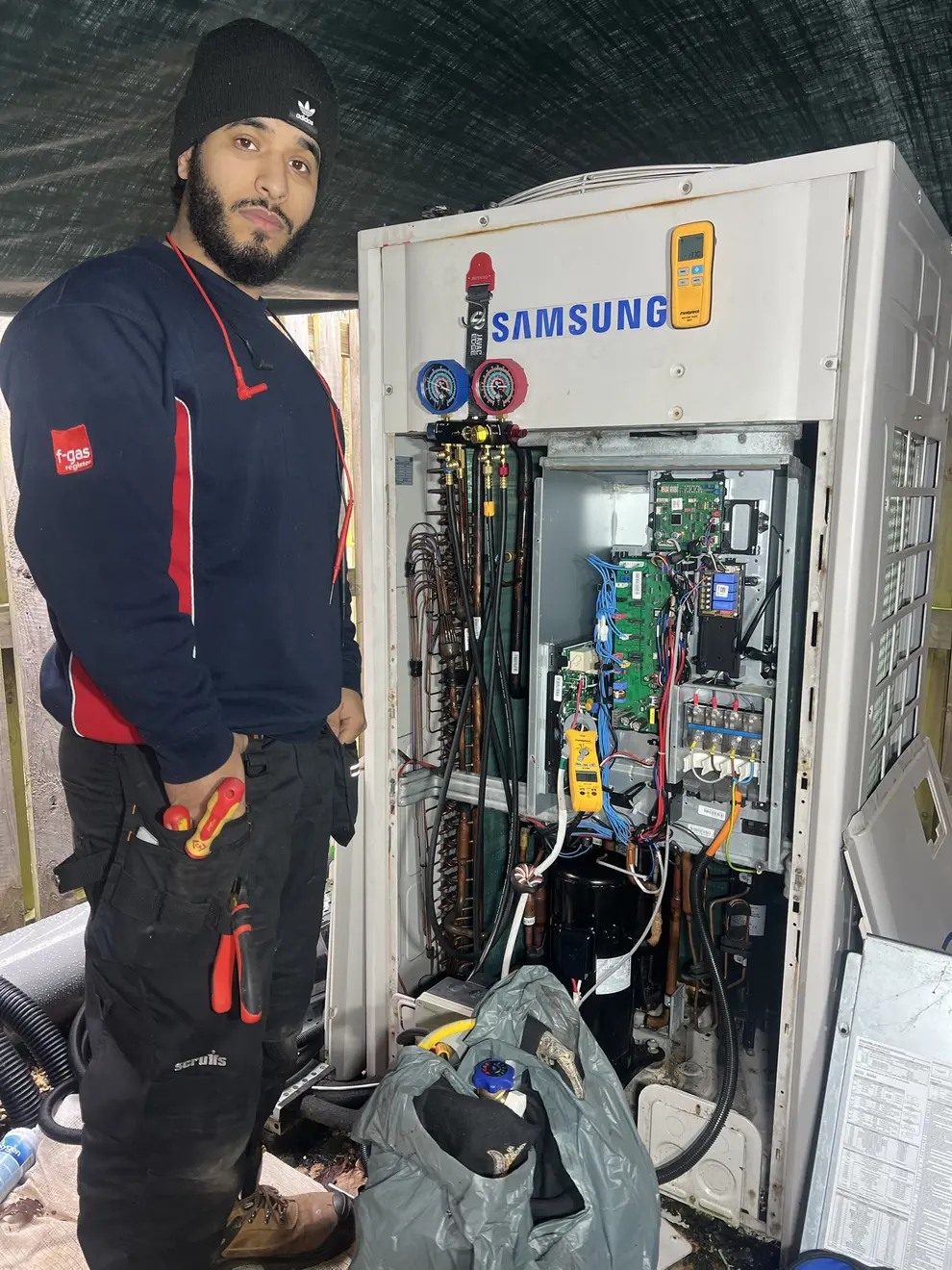 Engineer fault-finding on a Samsung VRF outdoor unit with gauges connected