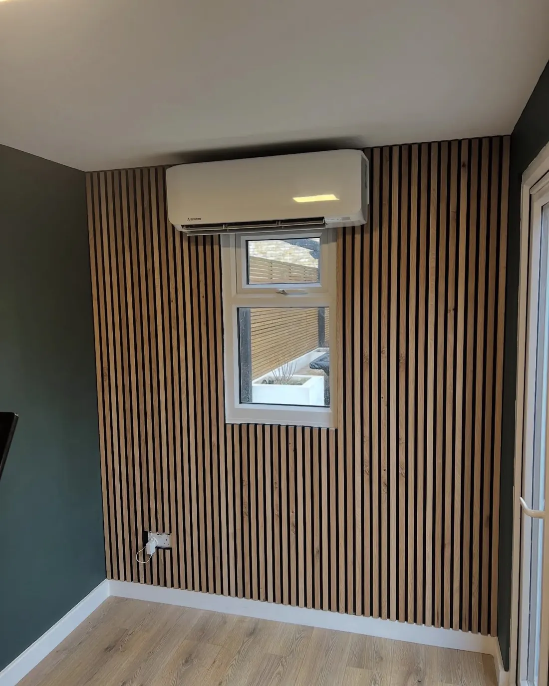 White wall unit on an oak-slat feature wall in a garden office