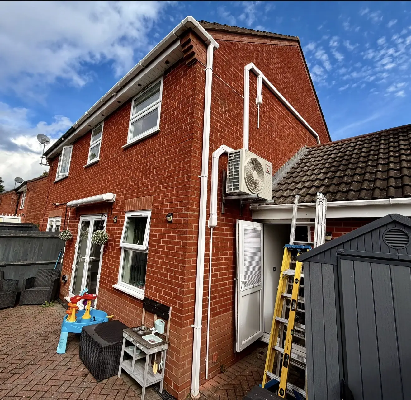 Home air conditioning on a red brick house with white trunking