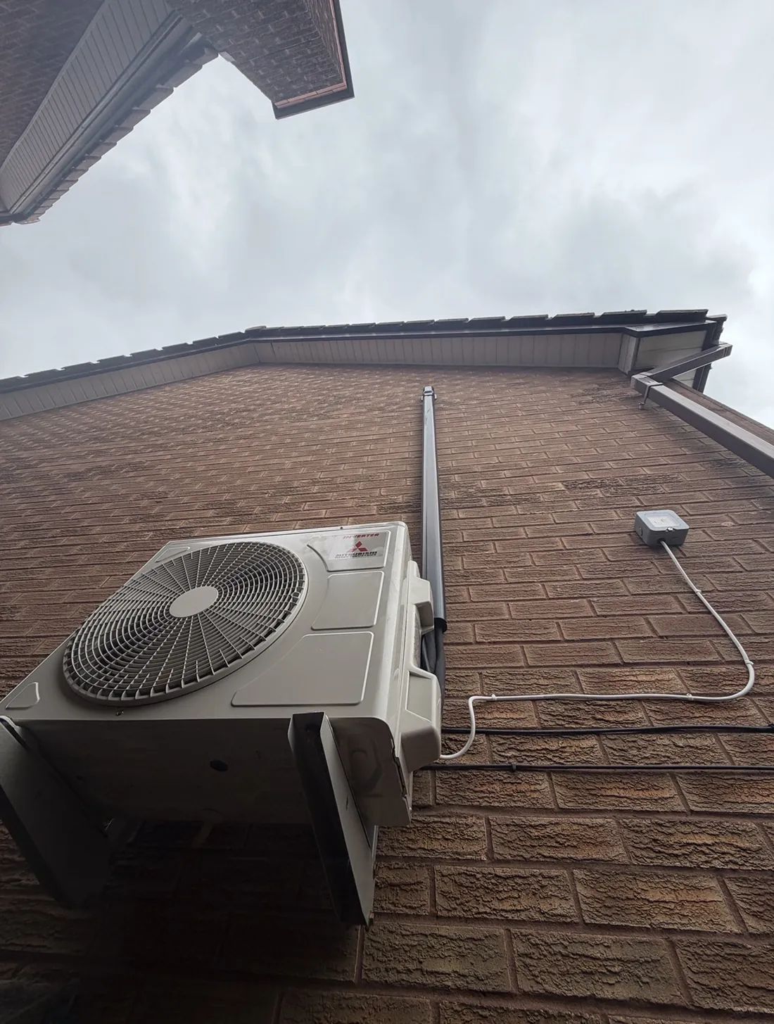 Mitsubishi Heavy Industries outdoor unit on a bracket on a brick gable with neat pipework