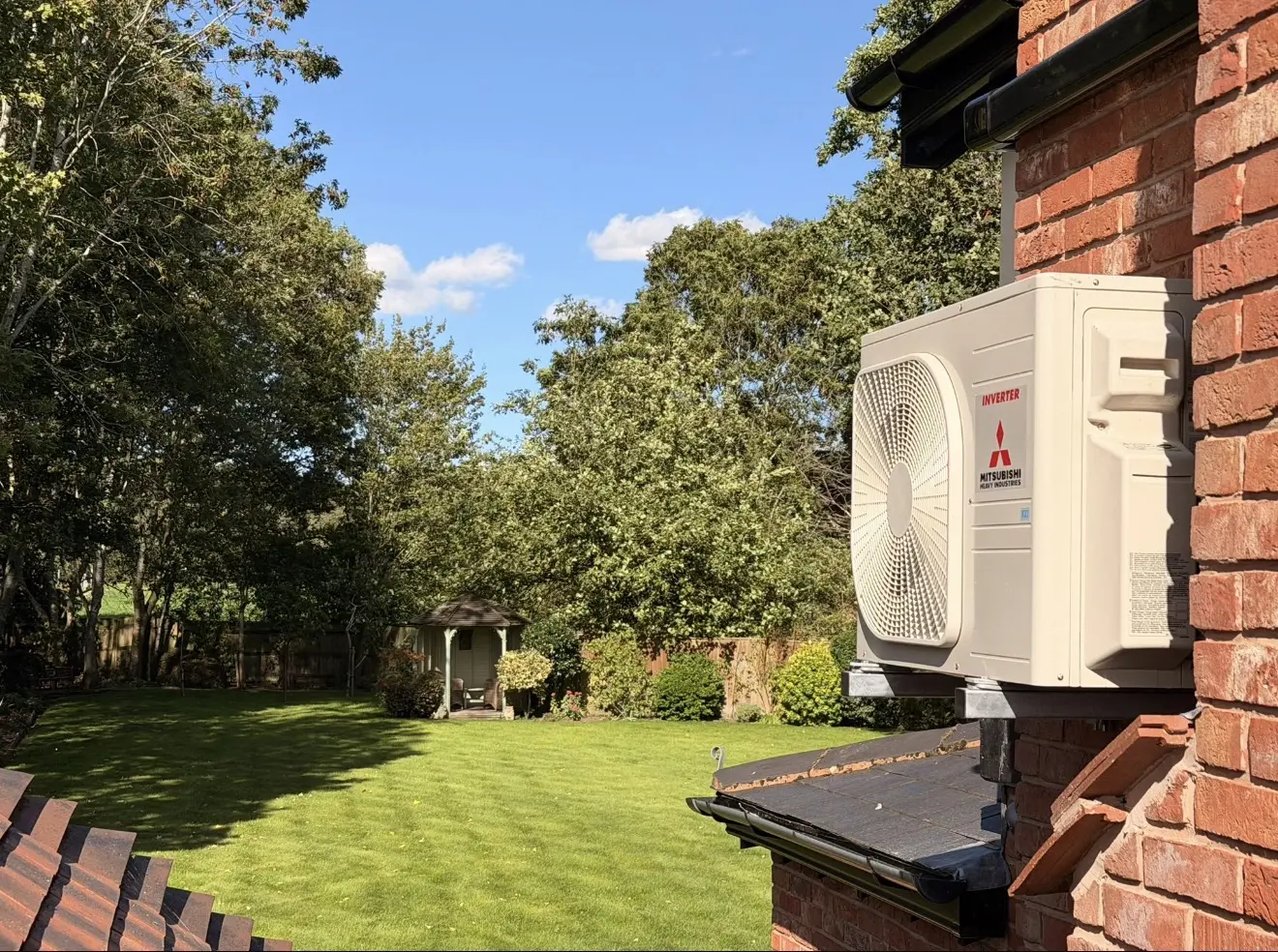 Mitsubishi Heavy Industries outdoor unit on a wall bracket overlooking a garden