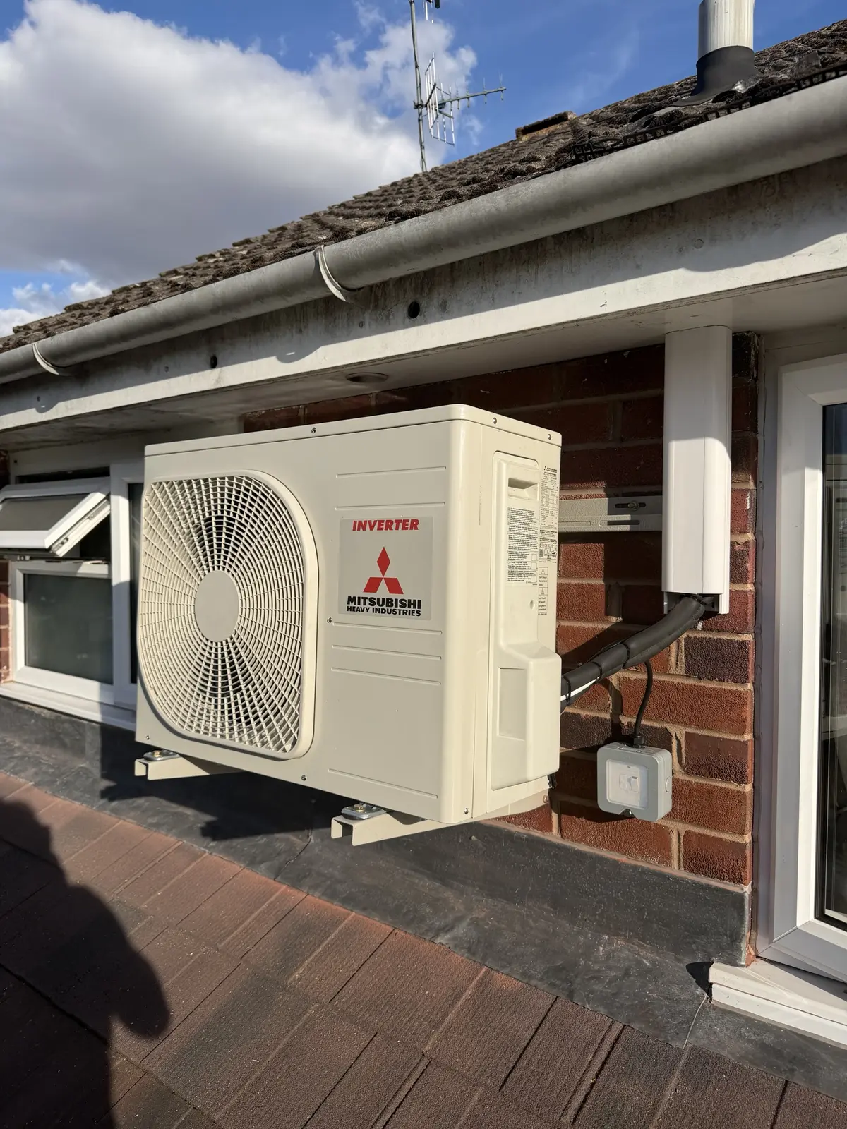 Mitsubishi Heavy Industries outdoor unit on a wall bracket above a flat roof