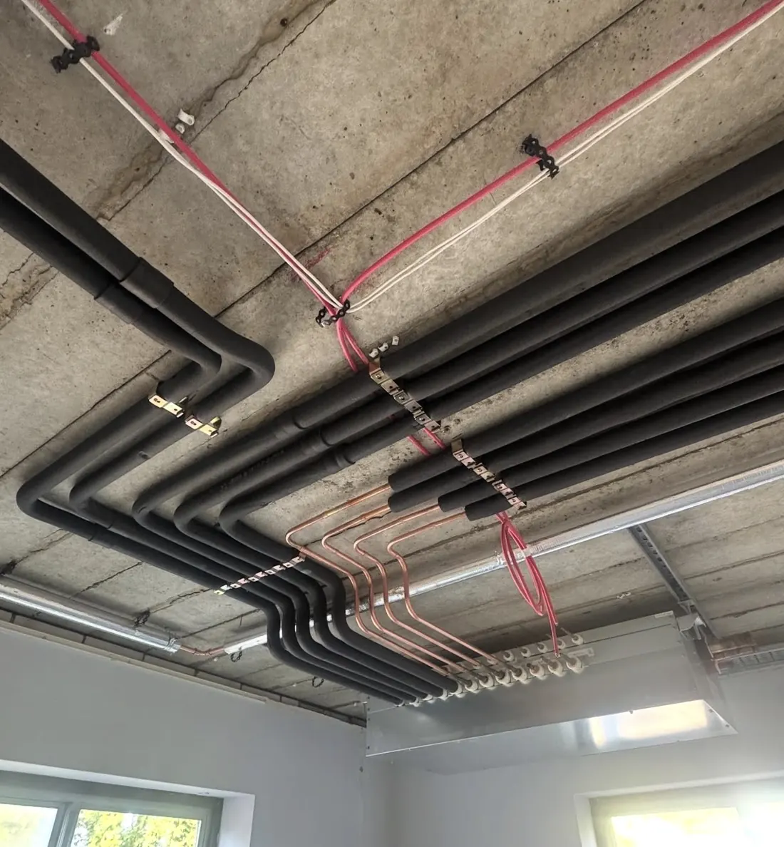 Neatly bent insulated and bare copper refrigerant pipework running to a branch controller