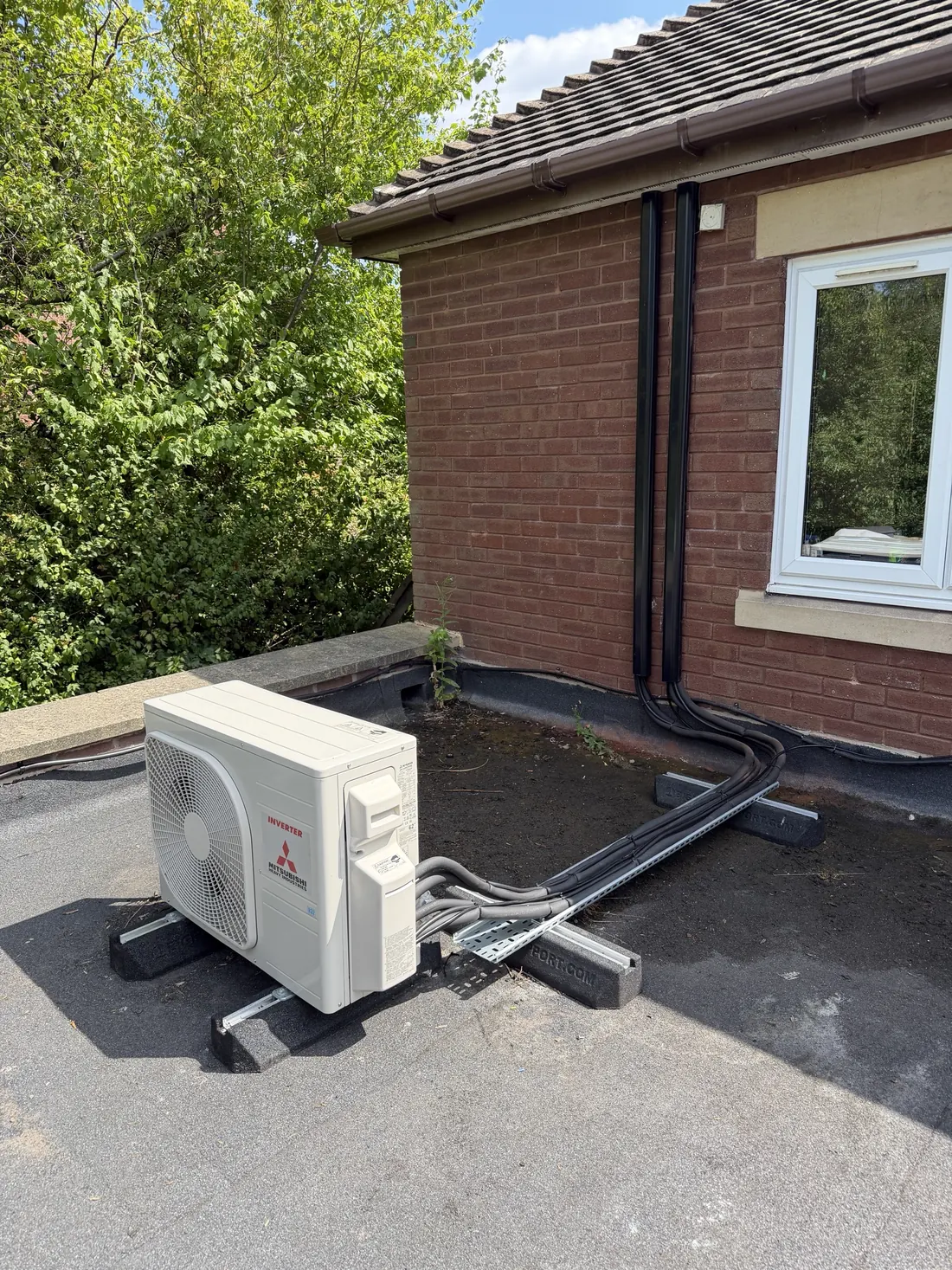 Mitsubishi Heavy Industries outdoor unit on a flat roof with twin black trunking routed up the wall