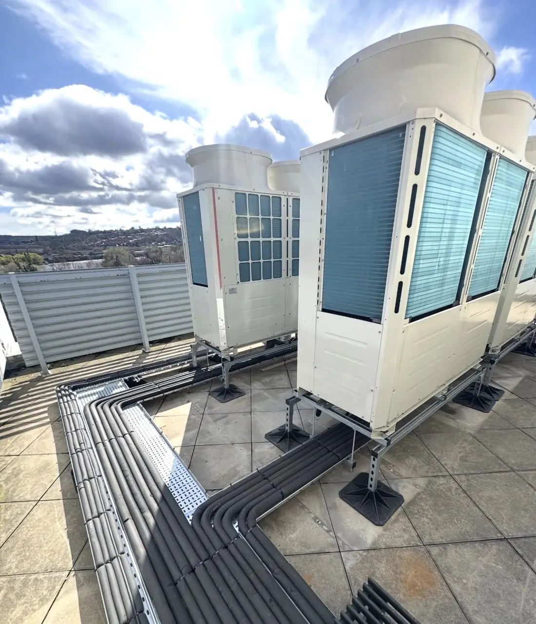 VRF outdoor units on a roof with insulated pipework routed in galvanised tray