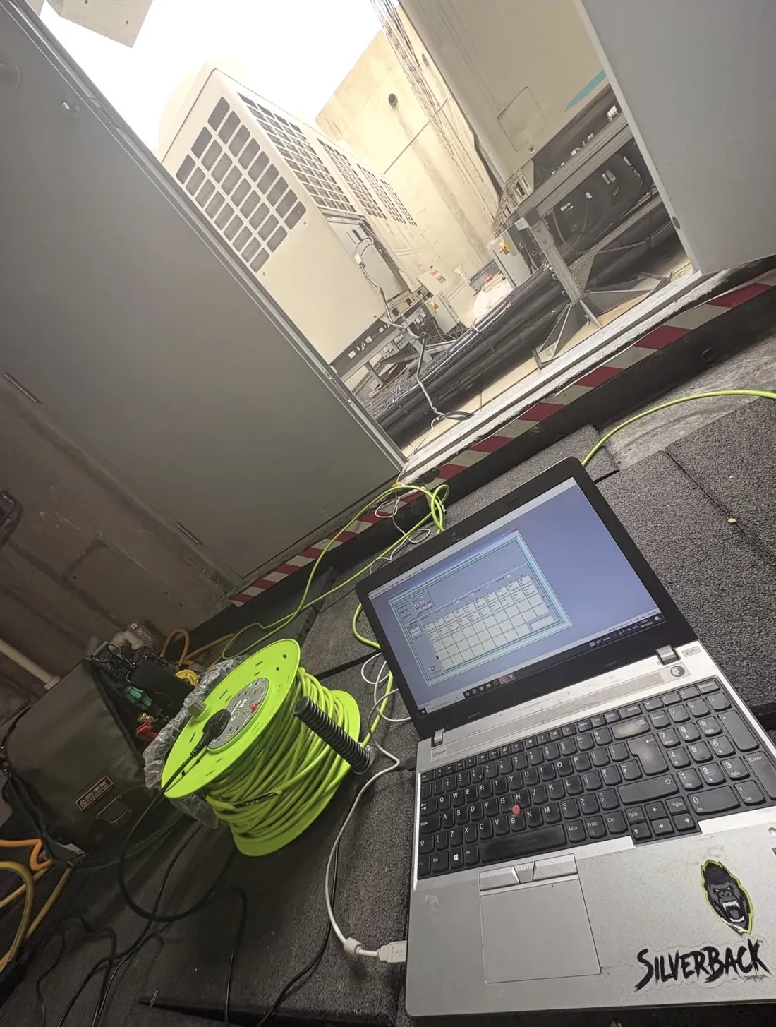 Engineer’s laptop and extension reel on a roof plant deck with VRV outdoor units behind