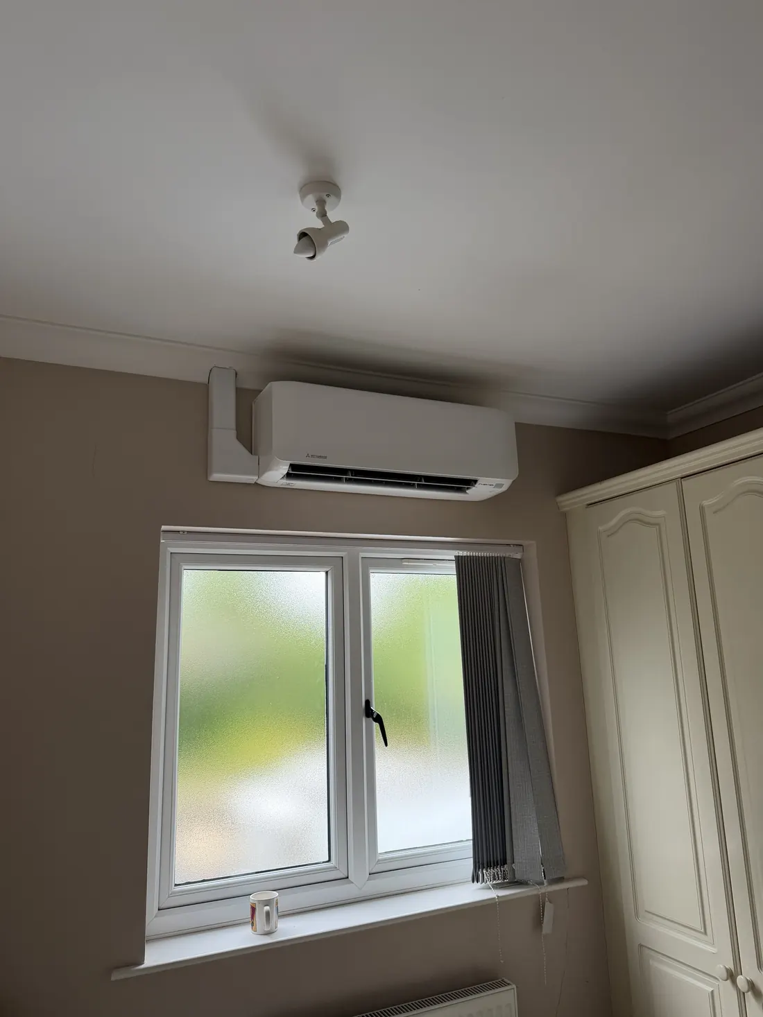 Mitsubishi wall unit above a bedroom window with white trunking